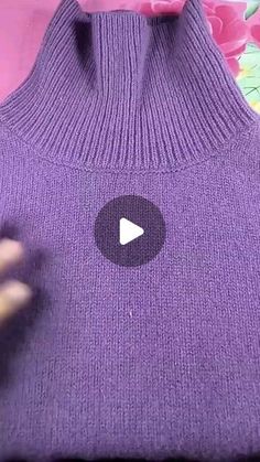 someone is using their fingers to press the button on a purple sweater