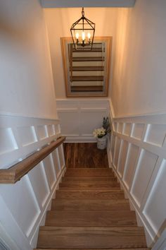 a light that is on in the ceiling above a stair case with wood floors and handrails