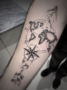 a man's arm with a compass and world map tattoo on the left forearm