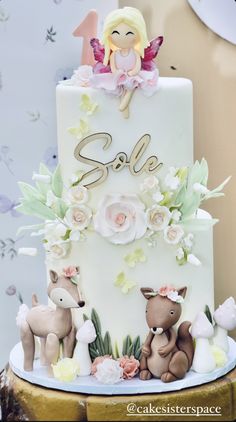 there is a white cake decorated with flowers and animals on the top, along with an angel figurine