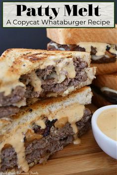 two grilled cheeseburger sandwiches stacked on top of each other next to a bowl of sauce