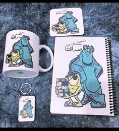 two coffee mugs with cartoon characters on them next to a notepad and keychain