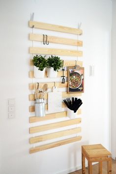 a wall mounted shelf with potted plants and utensils hanging on it's sides