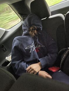 a person wearing a hoodie sitting in the back seat of a car