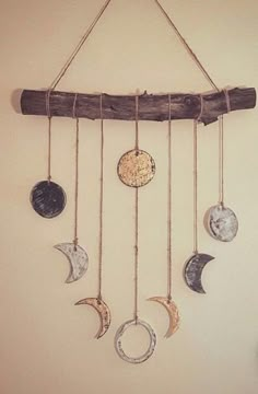 a wind chime with five different moon phases hanging from it's sides and a wooden stick attached to the wall