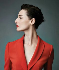 a woman with short black hair wearing a red suit