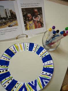 a blue and white plate sitting on top of a table next to a vase filled with pencils