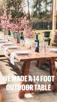 a wooden table with plates and wine glasses on it in the middle of a patio