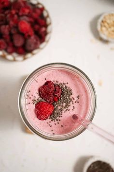 a smoothie with strawberries and chia seeds on the top is ready to be eaten