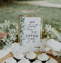 a table topped with cupcakes covered in frosting next to a sign that reads how sweet it is to be loved by you