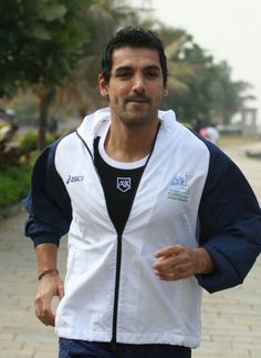 a man is running down the sidewalk in his white and blue jacket with black accents