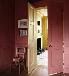 an open door leading into a room with pink walls and wood flooring on the other side