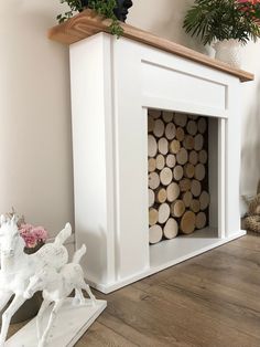 a white fireplace with logs in it and a horse figurine next to it