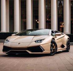 a white and gold colored sports car parked in front of a building with columns on either side