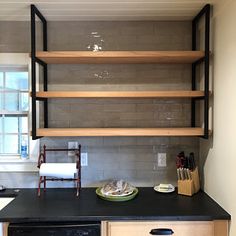 a kitchen with black counter tops and wooden shelves