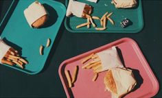 three trays with sandwiches and fries on them