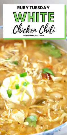 white chicken chili in a blue bowl with sour cream and green onion garnish