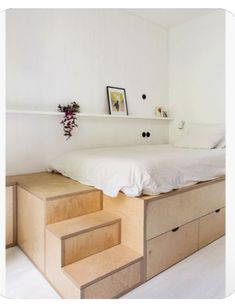 a bed sitting on top of a wooden dresser next to a white wall with pictures above it