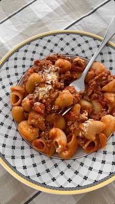 a plate full of pasta with meat and sauce on it, next to a fork