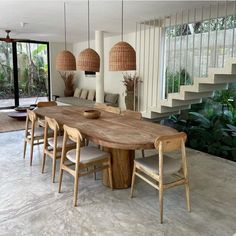 a large wooden table sitting in the middle of a living room next to a stair case