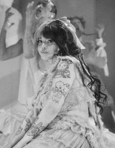 black and white photograph of a woman with tattoos on her arm sitting in front of other women