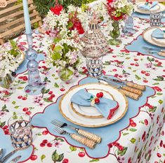 the table is set with plates, silverware and vases filled with colorful flowers