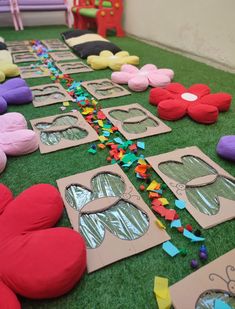 cardboard cut outs are laid out on the grass to make colorful paper flowers and butterfly shapes