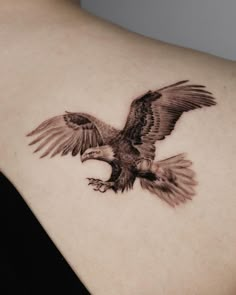 an eagle tattoo on the back of a woman's shoulder