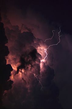 lightning strikes through the dark clouds in the night sky