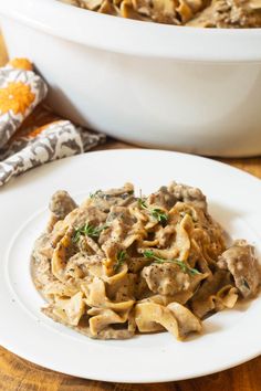 a white plate topped with pasta covered in gravy next to a casserole dish