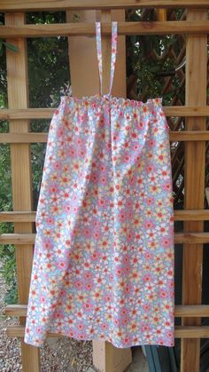 a pink and blue flowered cloth hanging from a wooden fence