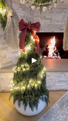 a fake christmas tree in a white pot with red ribbon and lights on the top