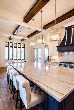 a large kitchen with marble counter tops and white chairs around the center island in front of an oven