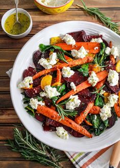 a plate with carrots, beets and feta cheese is on the table