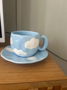 a blue cup and saucer sitting on top of a wooden table next to a computer