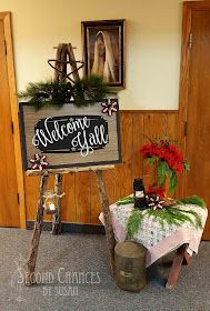 a sign that is sitting on the ground in front of a table with flowers and wine bottles