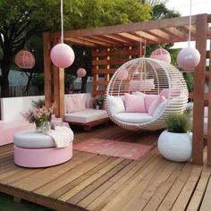 an outdoor living area with pink and white furniture, hanging lights, and round chairs