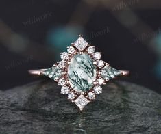 a fancy ring with green and white stones on it's side, sitting on top of a rock