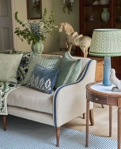 a living room filled with lots of furniture and pillows on top of a rug next to a table