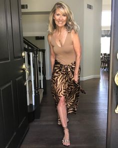 a woman is walking down the hallway in her home wearing a brown top and zebra print skirt