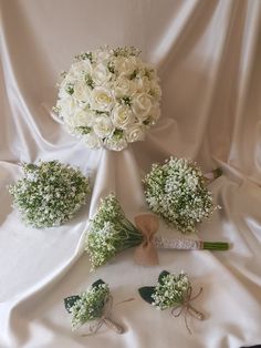 white roses and baby's breath are arranged on a table cloth for a wedding bouquet