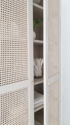 an open cabinet with white wicker doors