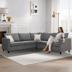 a woman sitting on top of a gray couch