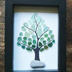 a tree made out of sea glass sitting in a frame