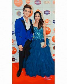 a man and woman standing next to each other on a red carpet