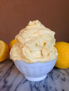 a white bowl filled with whipped cream next to two lemons