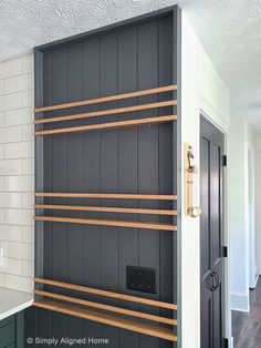 a black and white kitchen with wooden shelves on the wall next to an open door