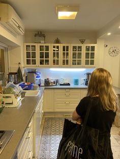 a woman carrying a black bag in a kitchen