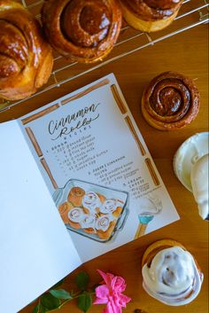 cinnamon rolls and pastries are sitting on a table with a recipe book next to them