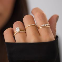 a woman's hand with three different rings on her fingers and one ring in the middle